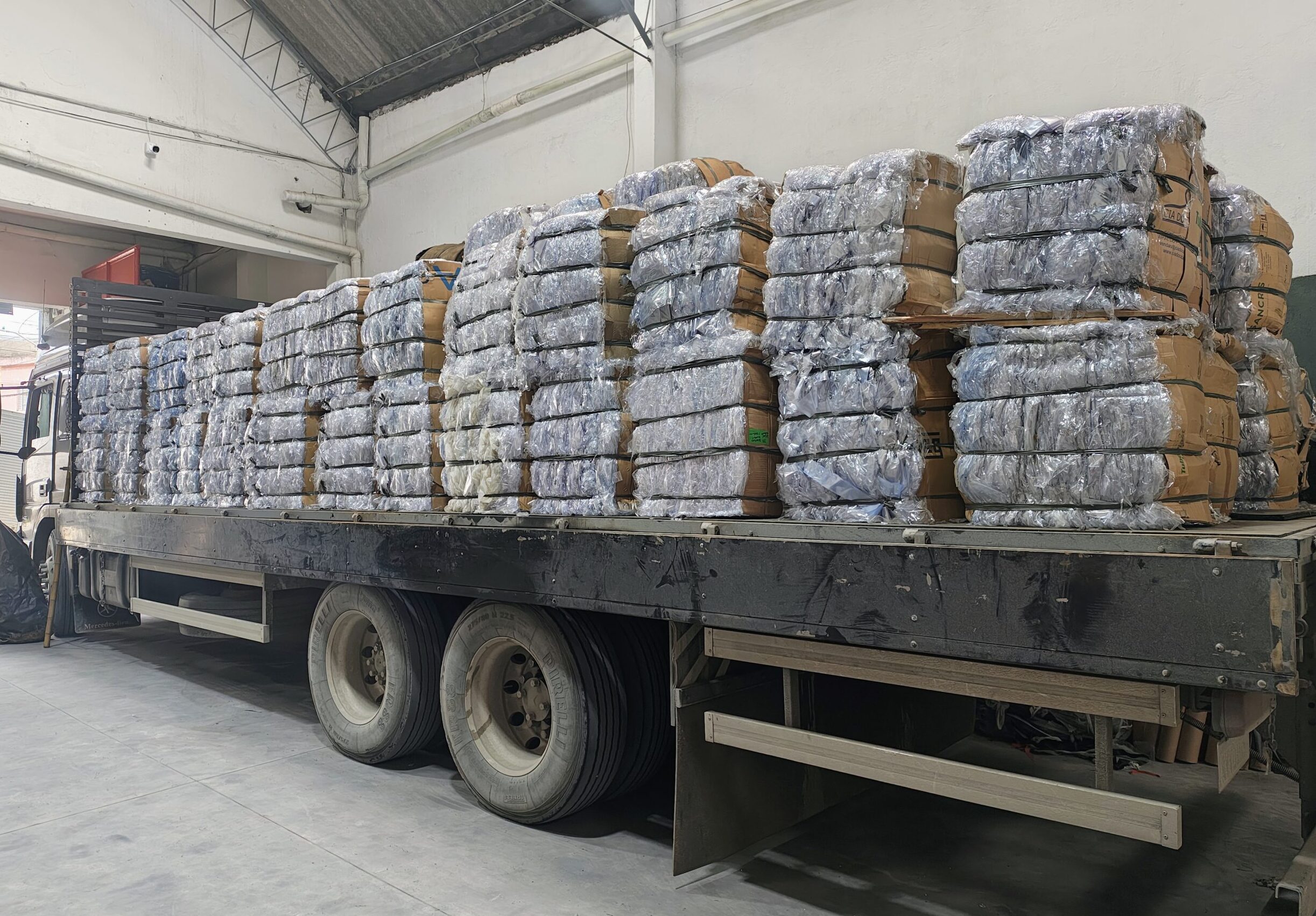 Caminhão carregado com fardos de aparas de PVC flexível para reciclagem industrial na Mega Plast Reciclagem